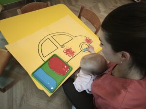 Dziecko maluje dłonią narysowany samochód.