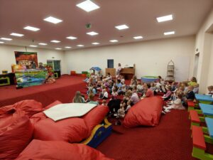 Dzieci wraz z opiekunkami oglądają teatrzyk kukiełkowy „Calineczka” w sali żłobka.