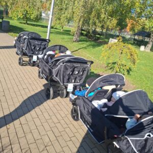 Dzieci ze żłobka podczas spacerów z wykorzystaniem nowych wózków sześcioosobowych i kolorowych węży spacerowych.
